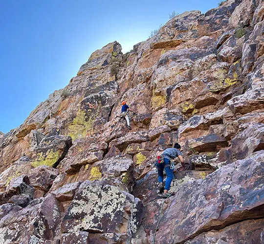 Rock climbing in Morocco with two climbers scaling a rugged cliff using ropes and gear